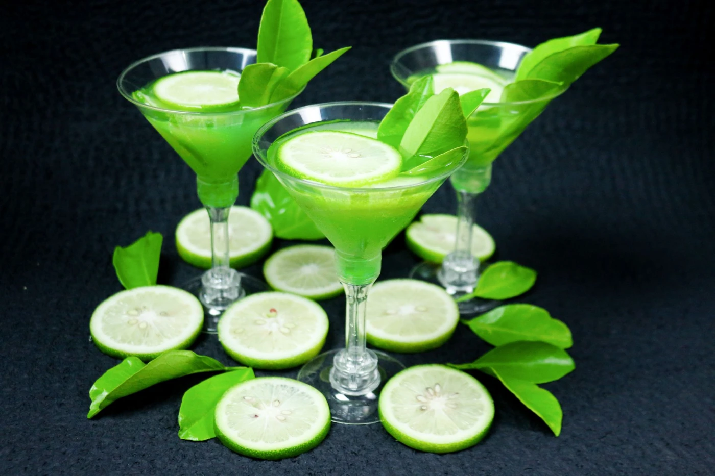 Absinthe Without Leave: Vibrant green cocktails garnished with lime slices and leaves, creating a refreshing still life.