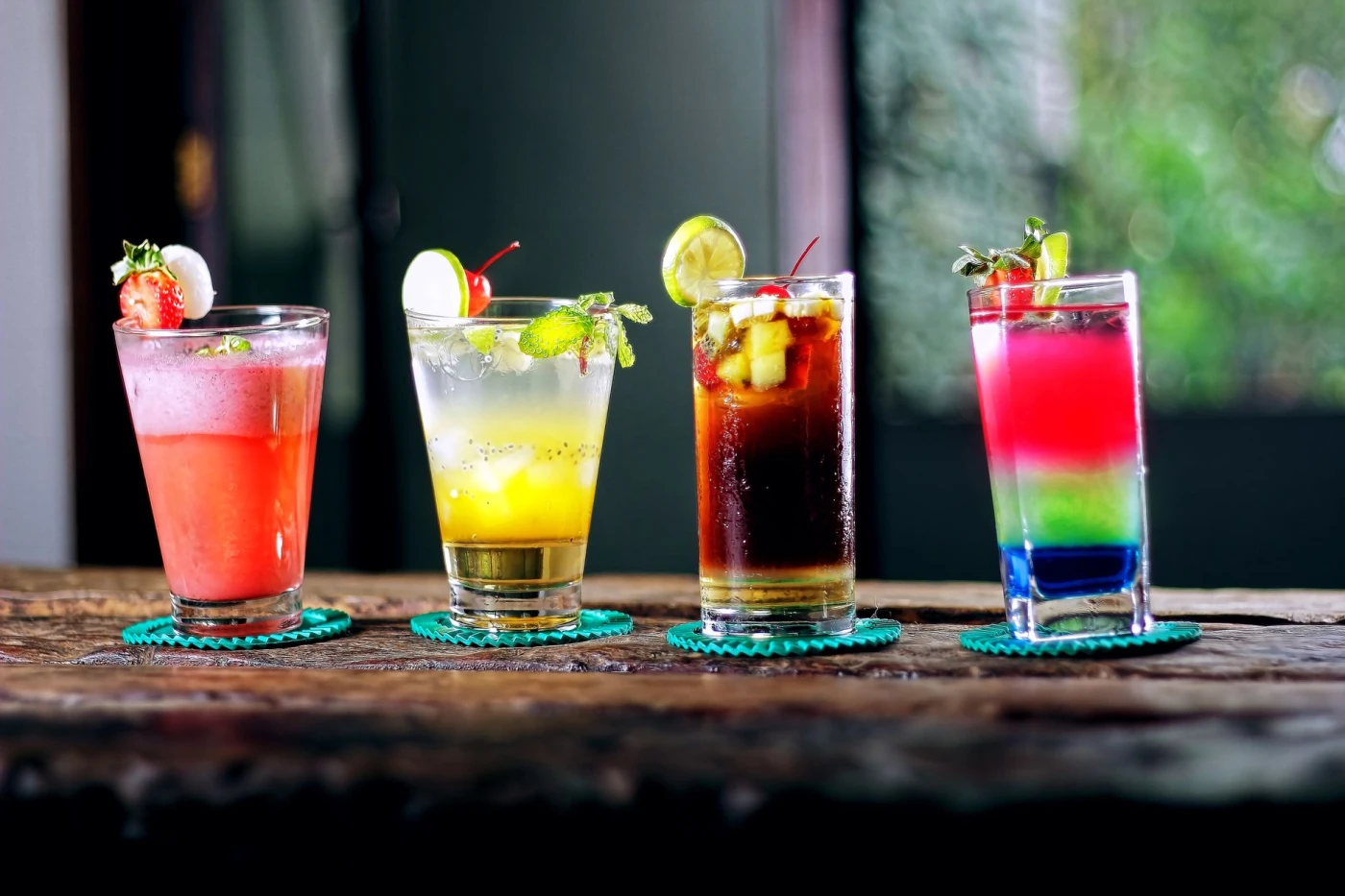Adam & Eve: Colorful assortment of cocktails on a rustic wooden table, perfect for a refreshing summer evening.