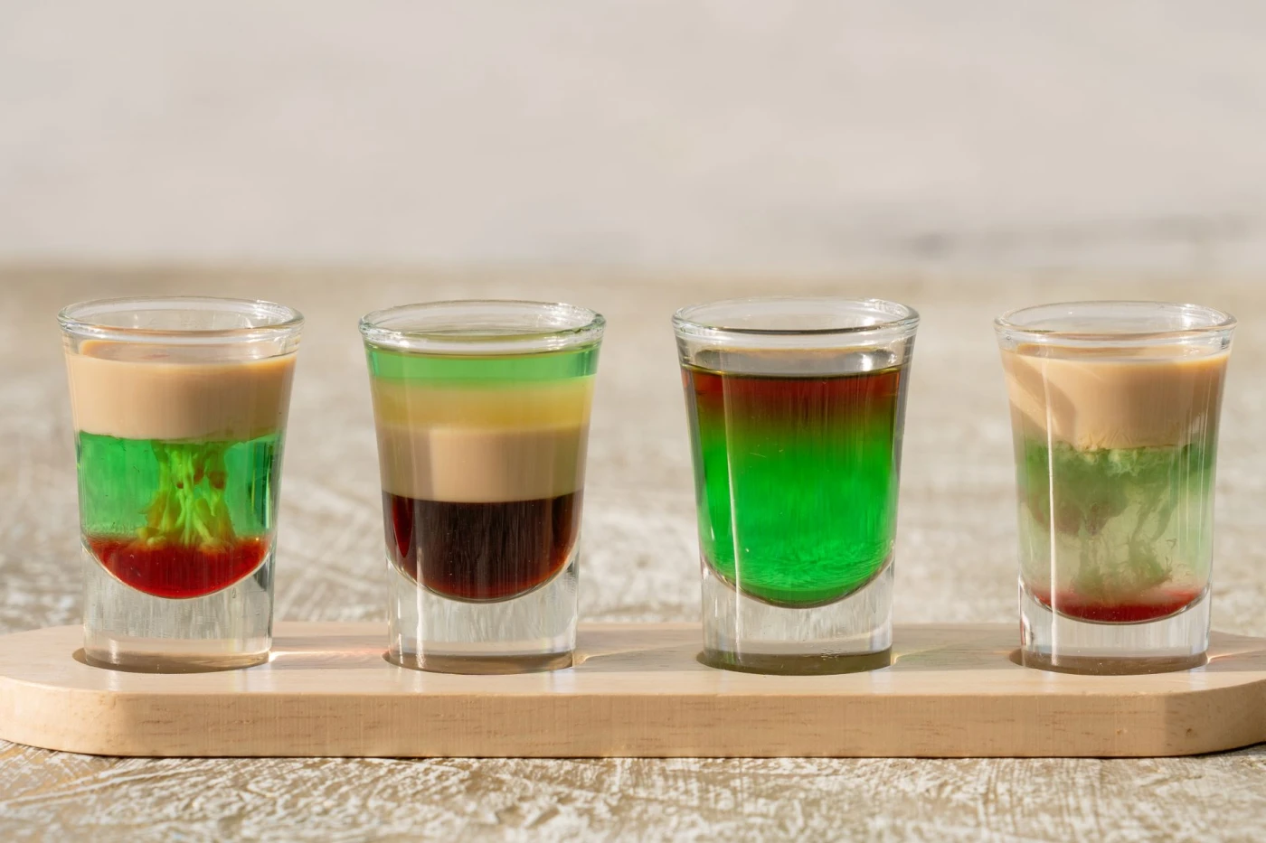 After Six Shot: Vibrant layered shots on a wooden tray, Dubai. Perfect for cocktail enthusiasts.