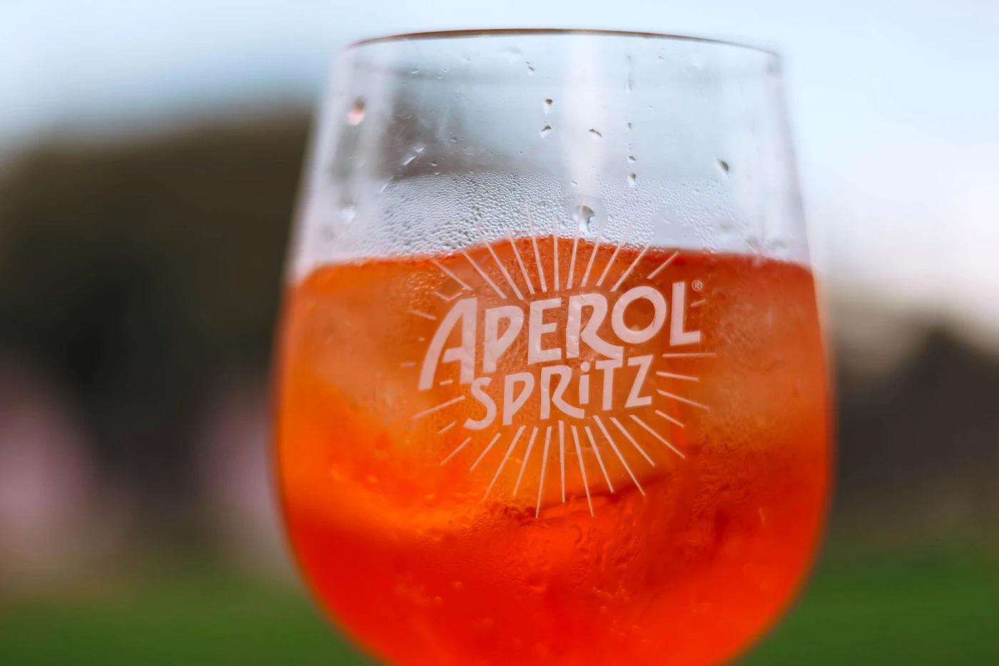 Aperol Spritz Pops: Refreshing Aperol Spritz cocktail on a sunny day with a blurred outdoor background.