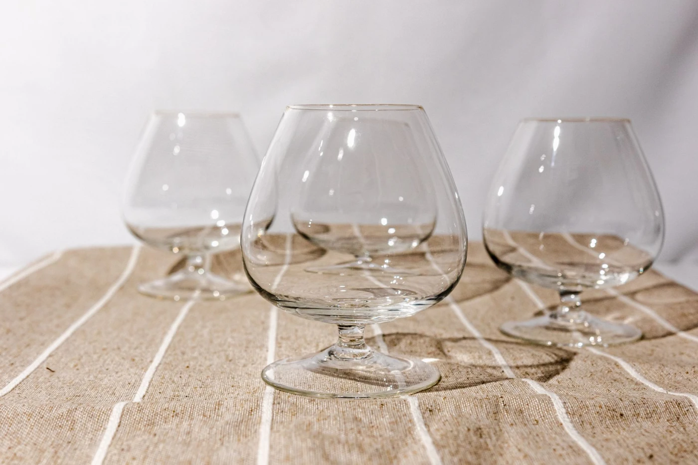 Brandy Crusta: Close-up of clean, empty brandy snifters on a rustic fabric table, perfect for bar or dining setting