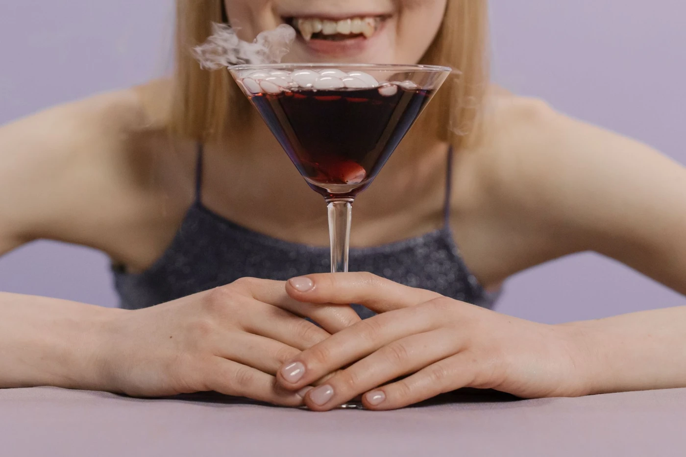 Dry Martini: A woman enjoying a spooky Halloween cocktail with dry ice in a martini glass.