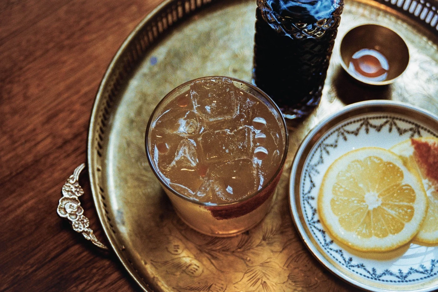 Golden Sbagliato: Chilled cocktail with ice cubes served with lemon slices on an elegant golden tray creates a perfect