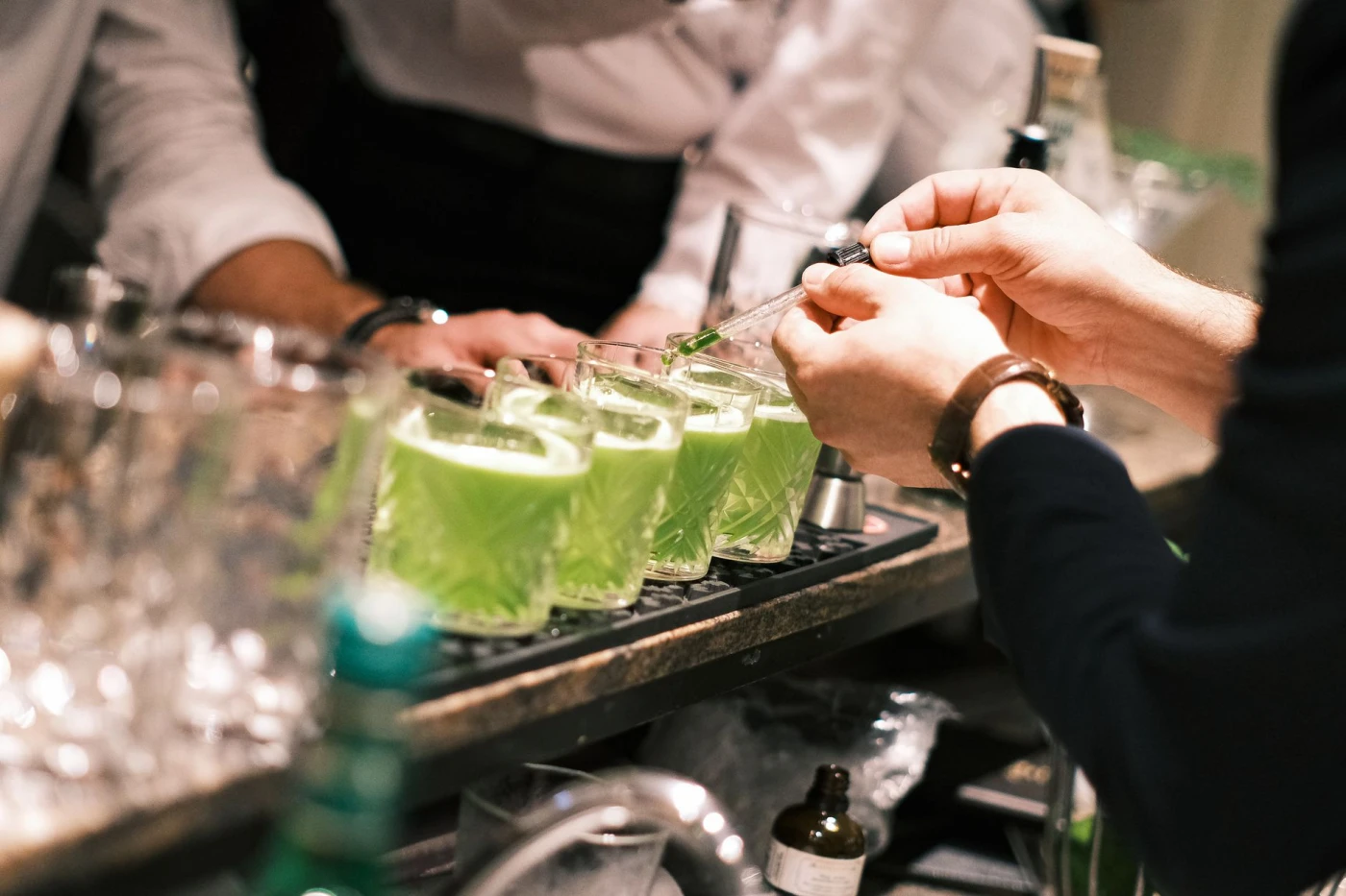 Green Hosting: Close-up of bartender preparing vibrant green cocktails in a stylish Parisian bar.