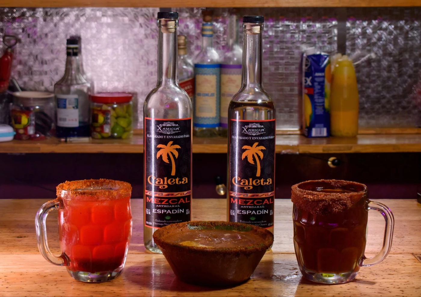 Mezcal Paloma ingredients with mezcal bottle and bar tools