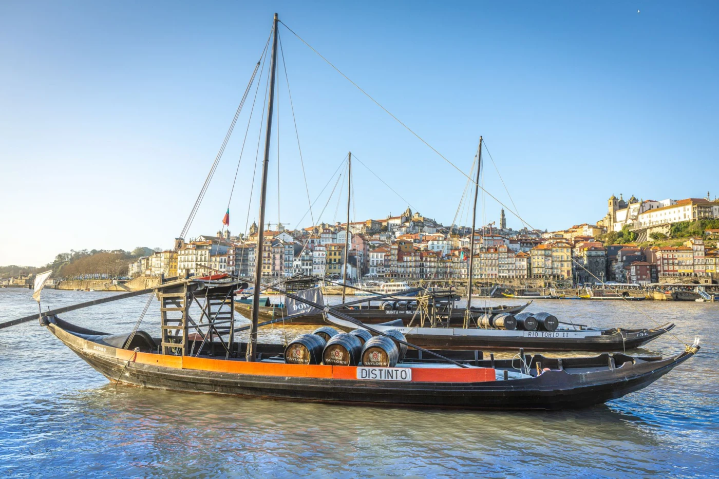 Porto Flip: Rabelo boats with wine barrels on the Douro River, Porto showcasing historic waterfront architecture