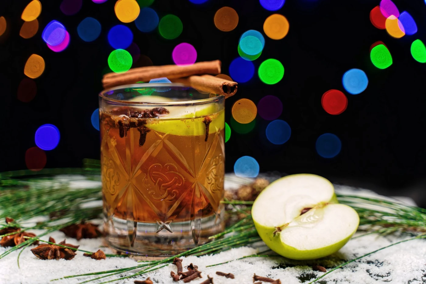 Spiced Orange Warmer – A Festive Winter Gin Cocktail: A festive cocktail with apples, cinnamon, and colorful lights, perfect for holiday celebrations.