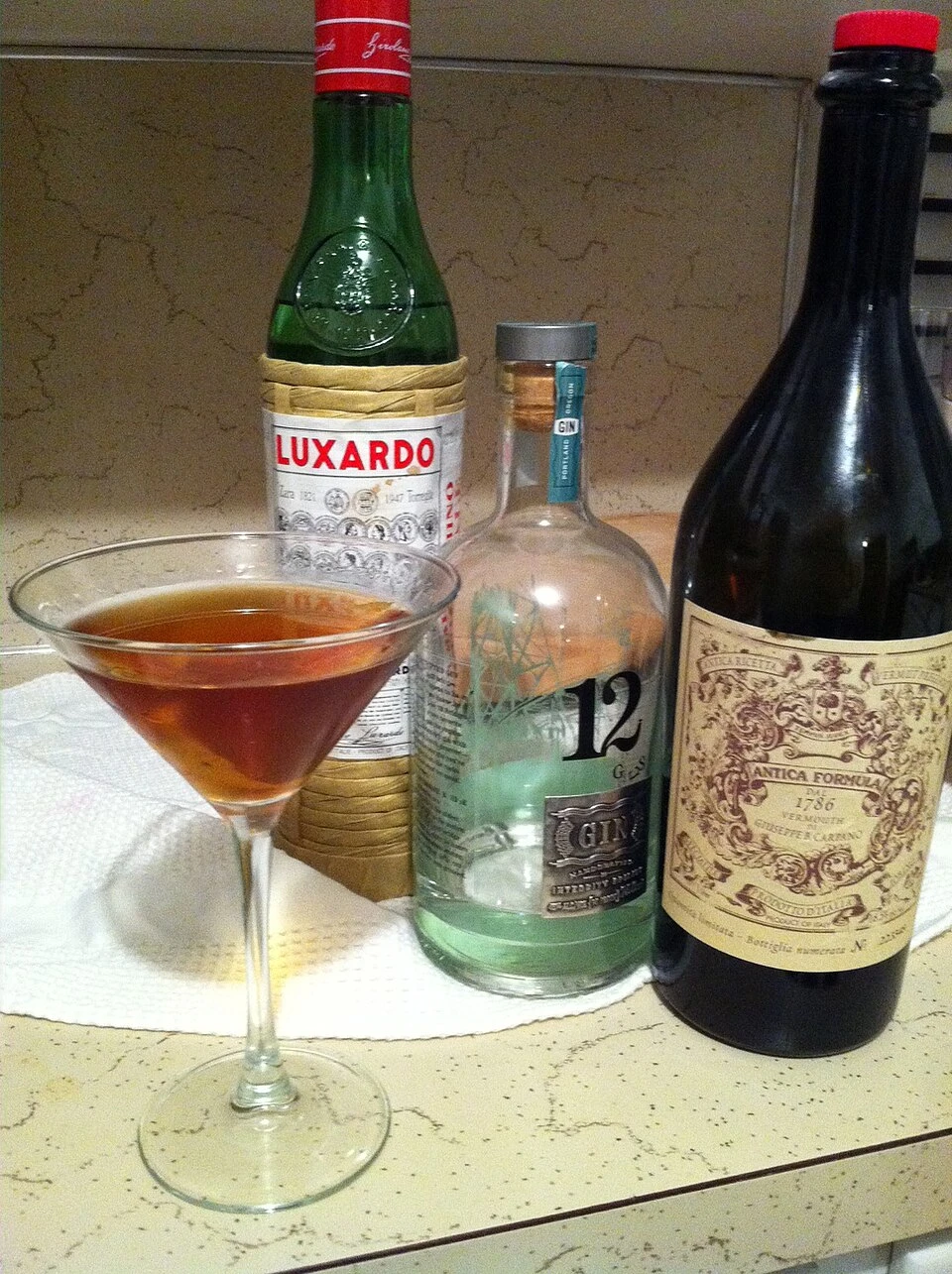 The Martinez Cocktail ingredients with gin bottle and bar tools